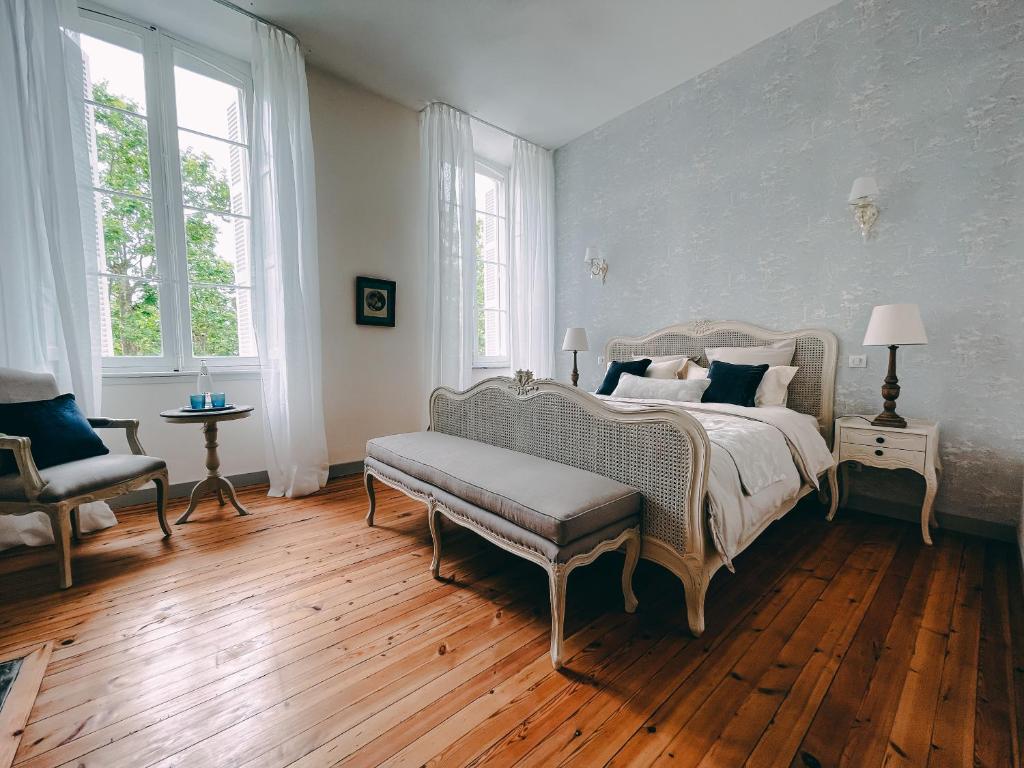 a bedroom with a bed and a bench and windows at Karma Chateau de Samary in Caux-et-Sauzens