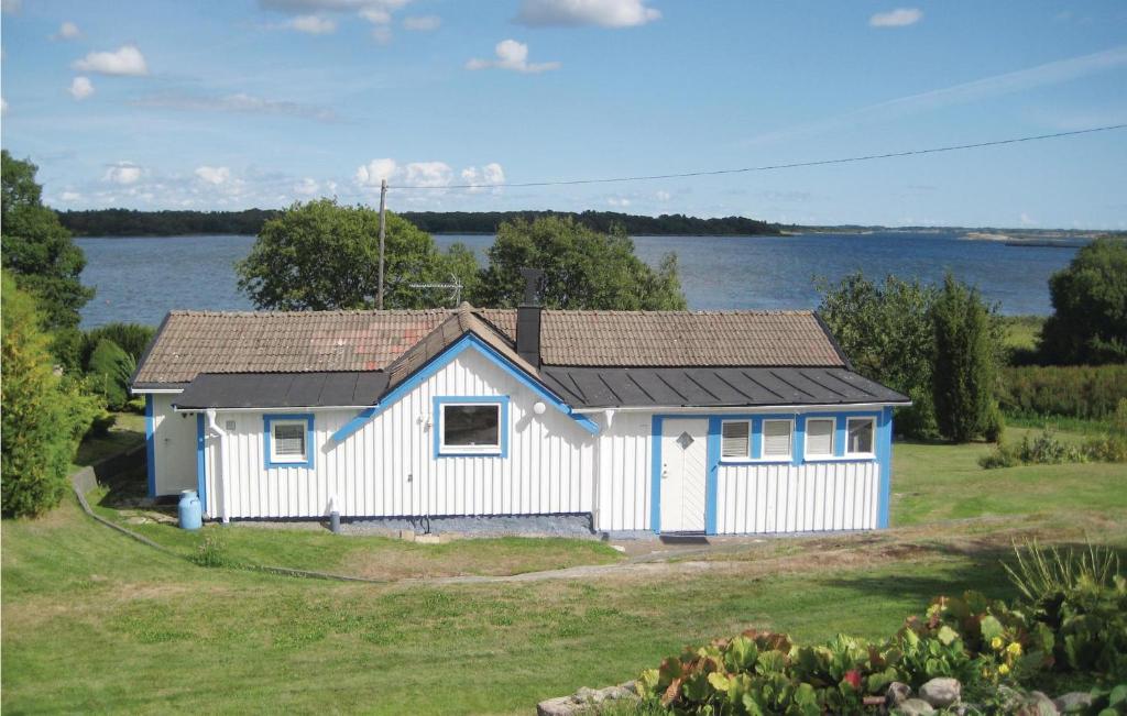 una piccola casa bianca di fronte a un lago di 1 Bedroom Nice Home In Sturk a Ryd