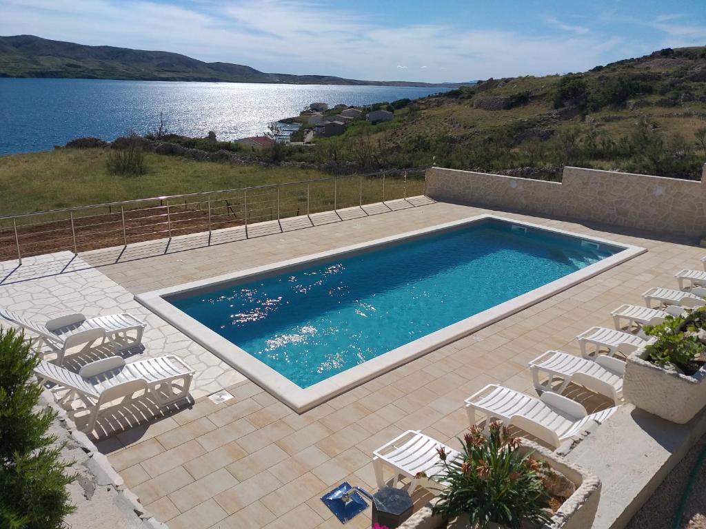 - une piscine avec des chaises et une vue sur l'eau dans l'établissement Apartment Ante K A1, à Metajna