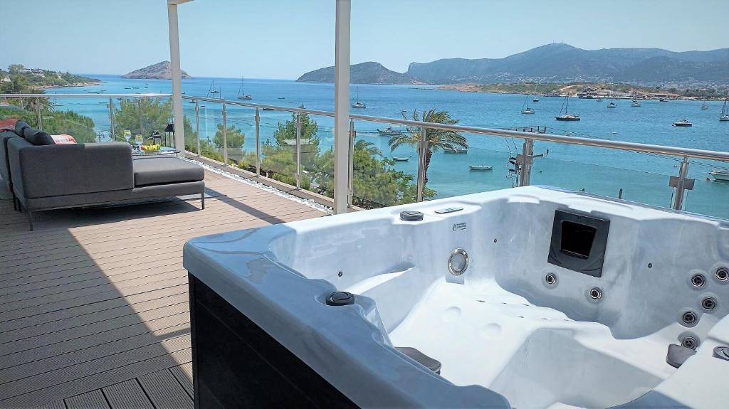 a bath tub sitting on a deck with a view of the ocean at PORTO BLUE LUXURY APARTMENT in Porto Rafti