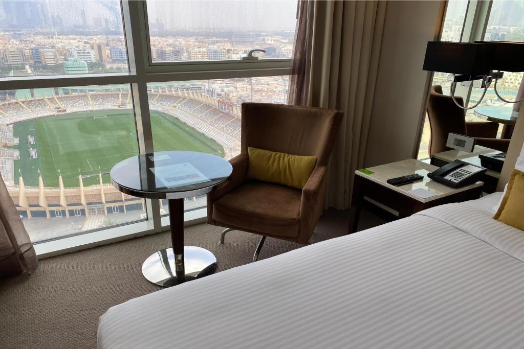 a hotel room with a bed and a desk and a window at Centro Al Manhal by Rotana in Abu Dhabi