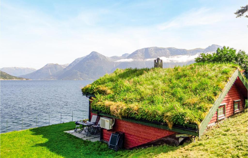 a house with a grass roof on the water at Raaen Hytteutleige 4 in Utne