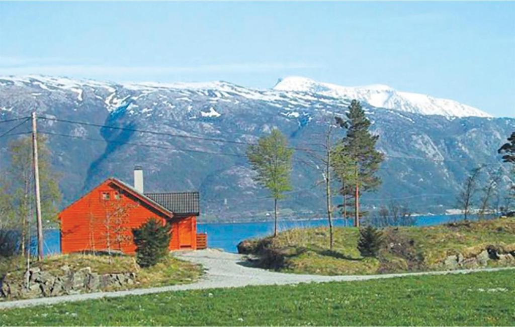 a red barn on a hill with snow covered mountains at Stunning Home In Varaldsy With 3 Bedrooms And Wifi in Gjuvsland