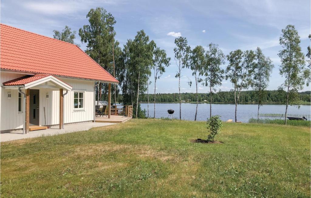 a white house with a red roof next to a lake at Cozy Home In Skillingaryd With Wifi in Skillingaryd
