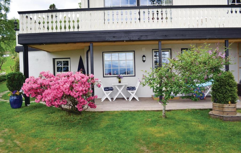 a house with a deck with a table and pink flowers at Beautiful Apartment In Norheimsund With House Sea View in Norheimsund