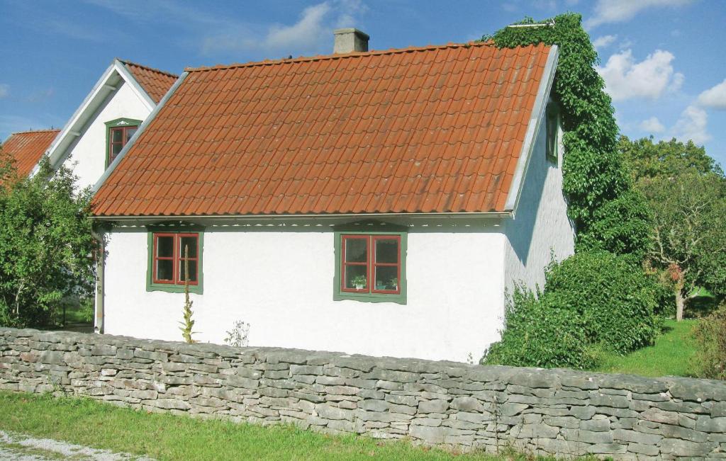 a white house with an orange roof and a stone wall at Beautiful Home In Katthammarsvik With 2 Bedrooms in Katthammarsvik