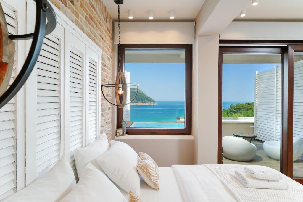 a bedroom with a white bed with a view of the ocean at Agorastos Hotel in Koinyra