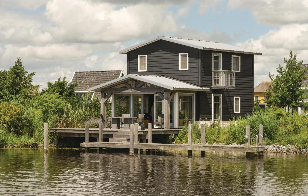 Ein schwarzes Haus auf einem Steg auf einem Wasserkörper in der Unterkunft Bodelaeke-Punter in Giethoorn