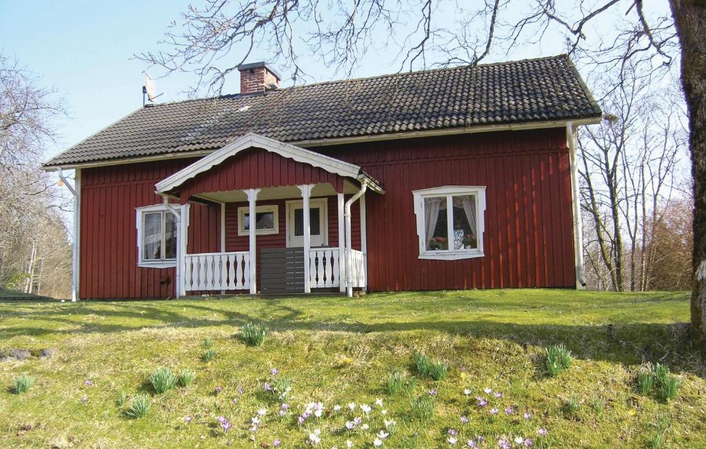 a red house with a white porch in a field at Beautiful Home In stra Frlunda With 3 Bedrooms And Sauna in Östra Frölunda