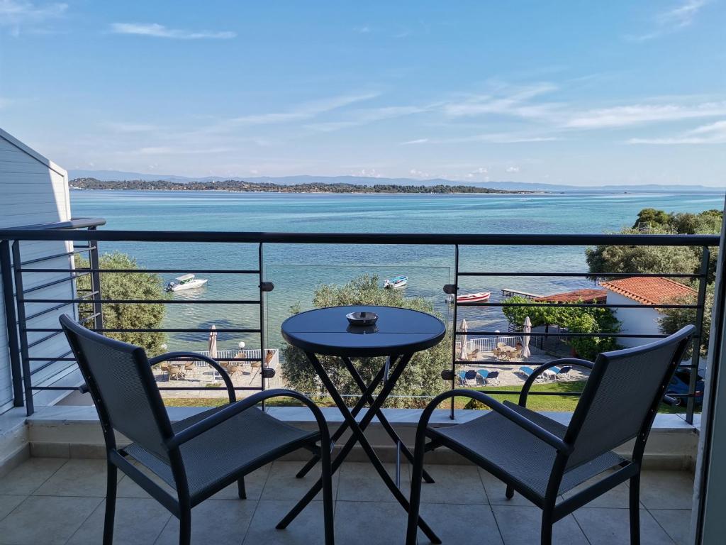 uma varanda com mesa e cadeiras e vista para a água em Vourvourou Hotel em Vourvourou