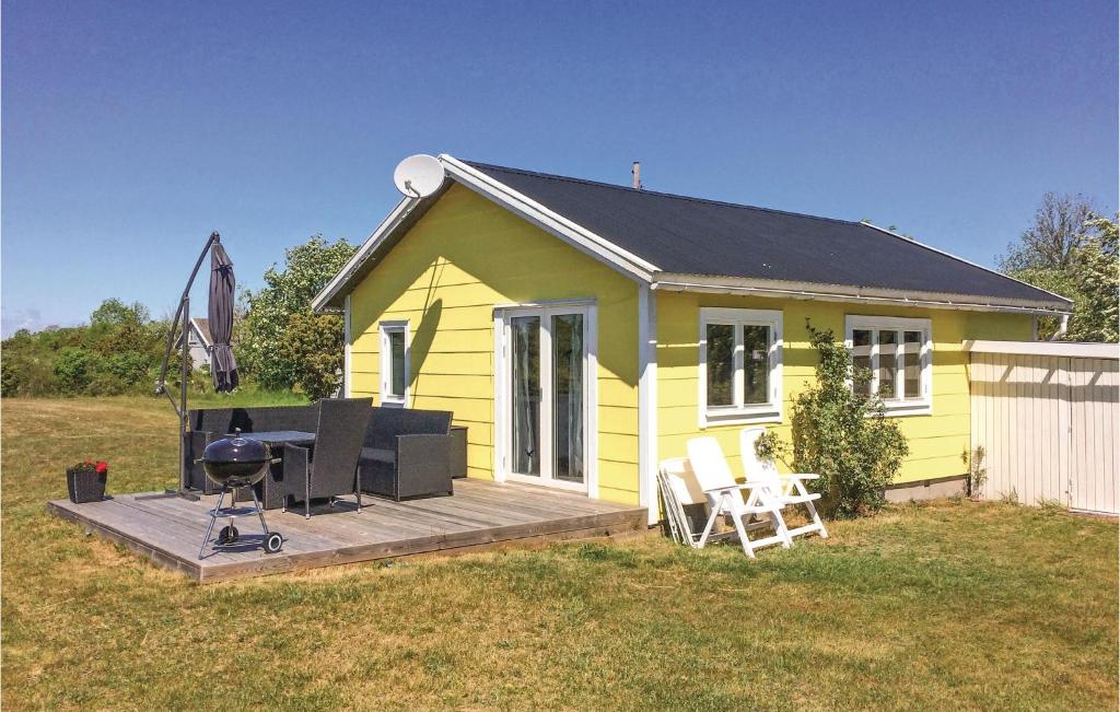 ein kleines gelbes Haus mit einem Grill auf einer Terrasse in der Unterkunft Stunning Home In Lttorp With Wifi in Löttorp