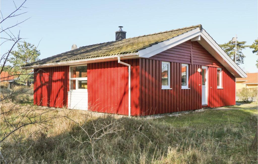 a red house with a white door on a field at Frische Brise 22 - Dorf 3 in Priwall