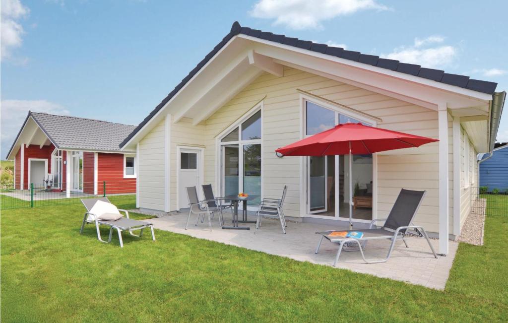 ein Haus mit einer Terrasse mit Stühlen und einem roten Regenschirm in der Unterkunft Amazing Home In Dagebll With 2 Bedrooms, Sauna And Wifi in Dagebüll