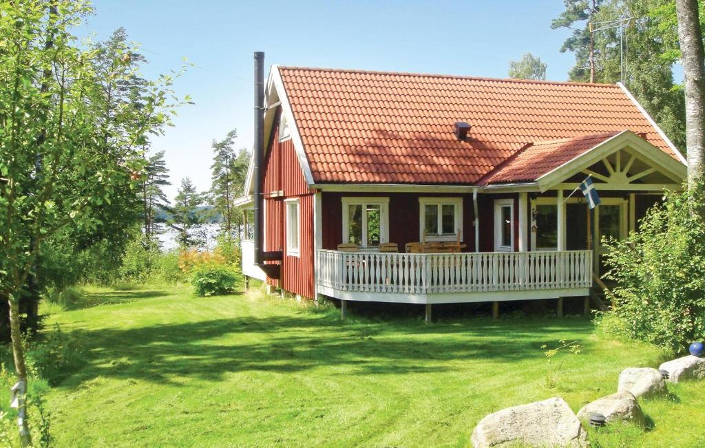 uma pequena casa vermelha com um alpendre branco em Amazing Home In Annerstad With 2 Bedrooms, Sauna And Wifi em Romborna