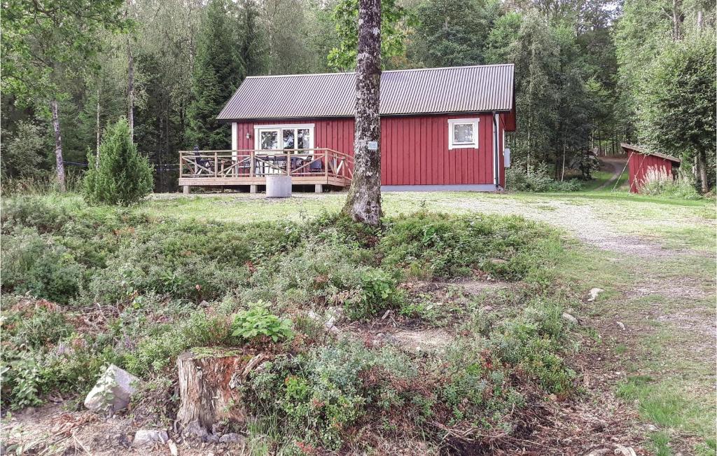 a red cabin with a tree in front of it at 2 Bedroom Awesome Home In Torup in Hallaböke