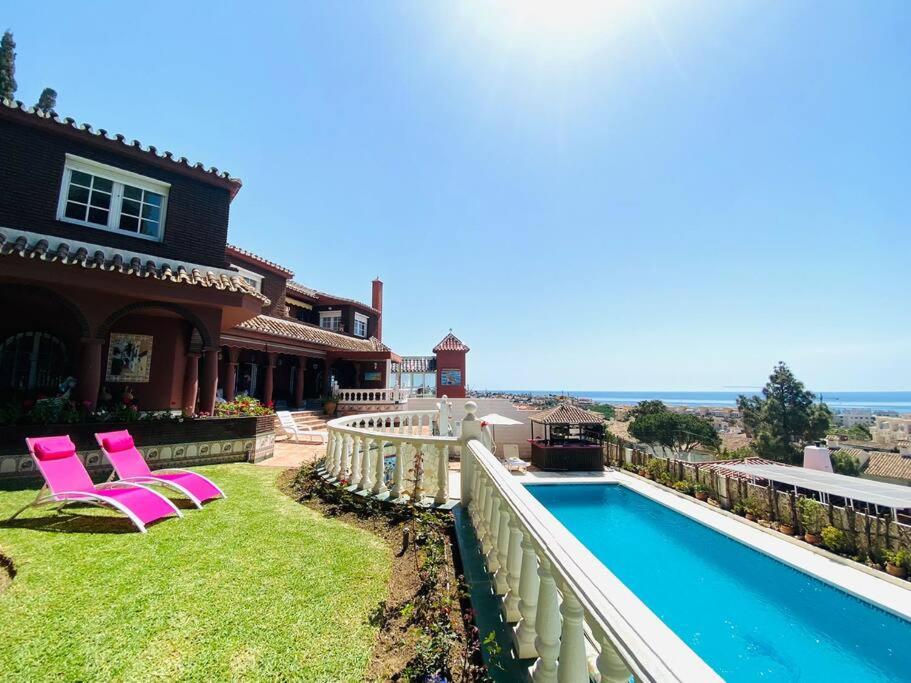 een huis met roze stoelen en een zwembad bij Villa Geneviève Costa del Sol in Mijas Costa