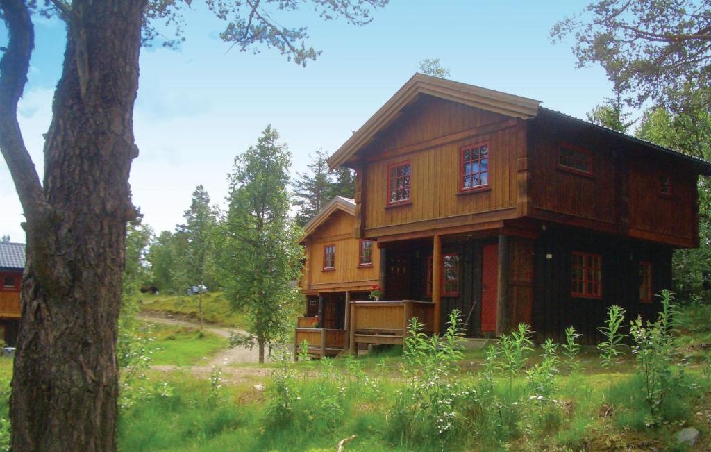 een houten huis in een veld met een boom bij Gorgeous Home In Ringebu With House A Mountain View in Odlo