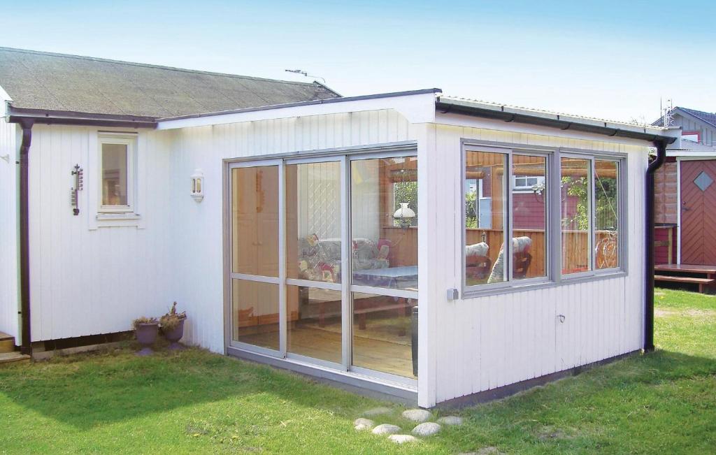 a small white shed with glass doors in a yard at Nice Home In Halmstad With Kitchen in Halmstad