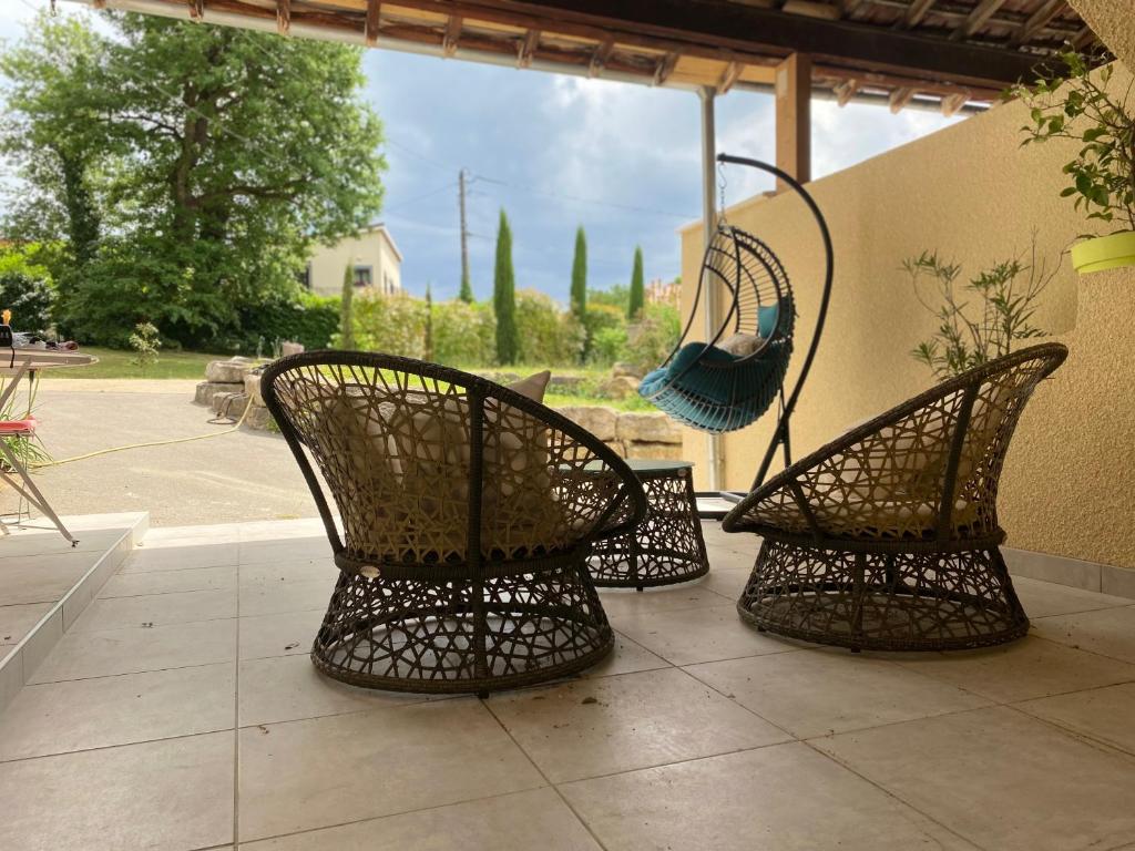 três cadeiras sentadas num pátio com um guarda-sol em Les Berouds em Salaise-sur-Sanne