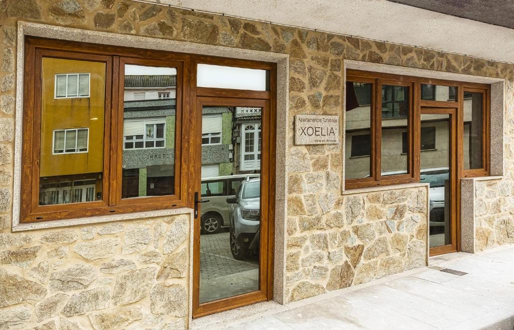 un edificio de piedra con tres ventanas y un cartel en él en Xoel, en Muxía