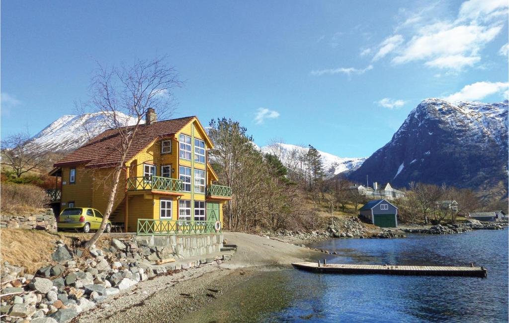 a yellow house next to a river with snow covered mountains at Lovely Apartment In Rosendal With Kitchen in Rosendal