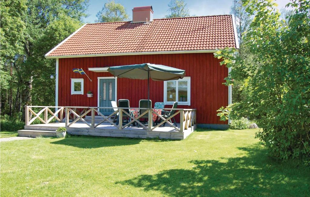 un cottage rouge avec deux chaises et un parasol dans l'établissement Nice Home In Vrigstad With 2 Bedrooms And Wifi, à Vrigstad