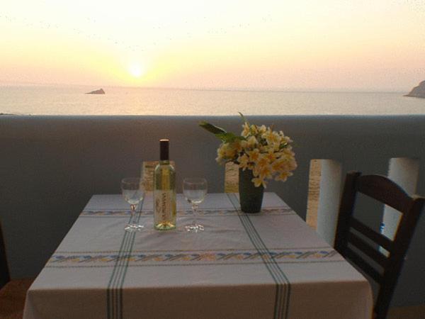 a table with a bottle of wine and wine glasses at Archipelagos Apartments in Arkasa