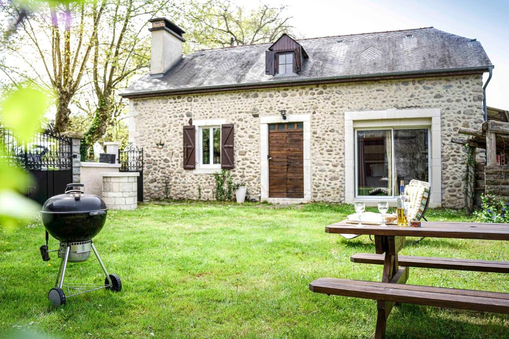 a grill and picnic table in front of a house at Maison de charme à proximité de Pau - 3 chambres - 6 p - Jardin in Sendets