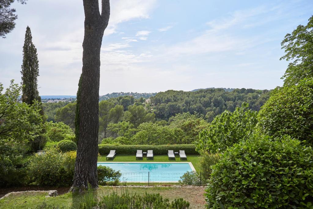 uma piscina num jardim com cadeiras e uma árvore em Appart13 piscine chauffée de luxe Belvoir13 à 10 min d Aix em Aix-en-Provence