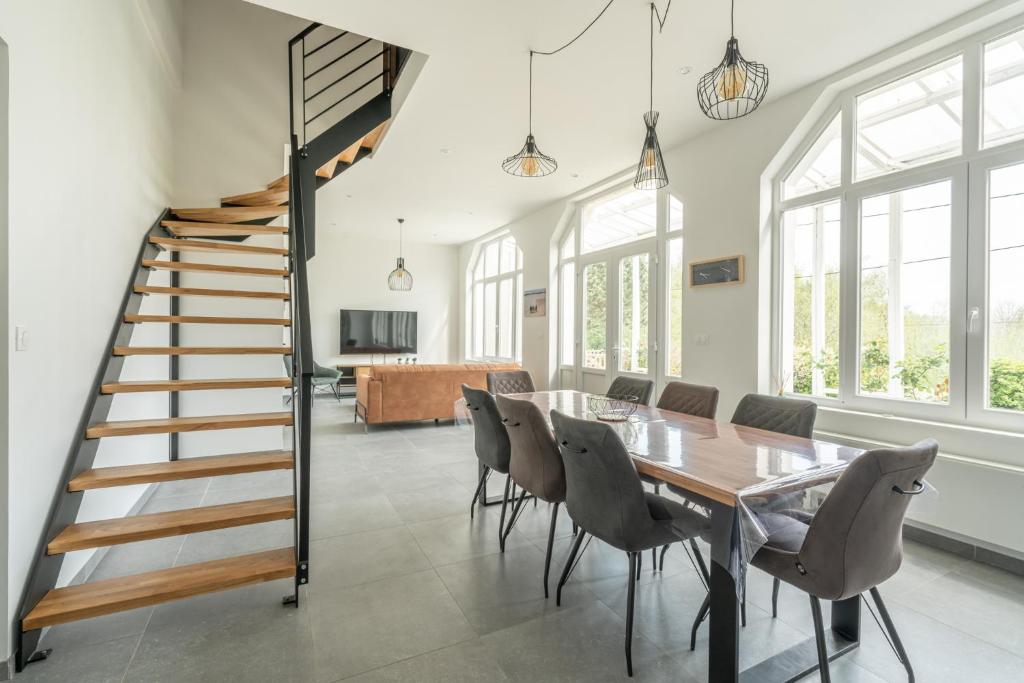 uma sala de jantar com uma mesa e cadeiras e uma escadaria em Lumière espace et convivialité à 2 pas de Wimereux em Wimille