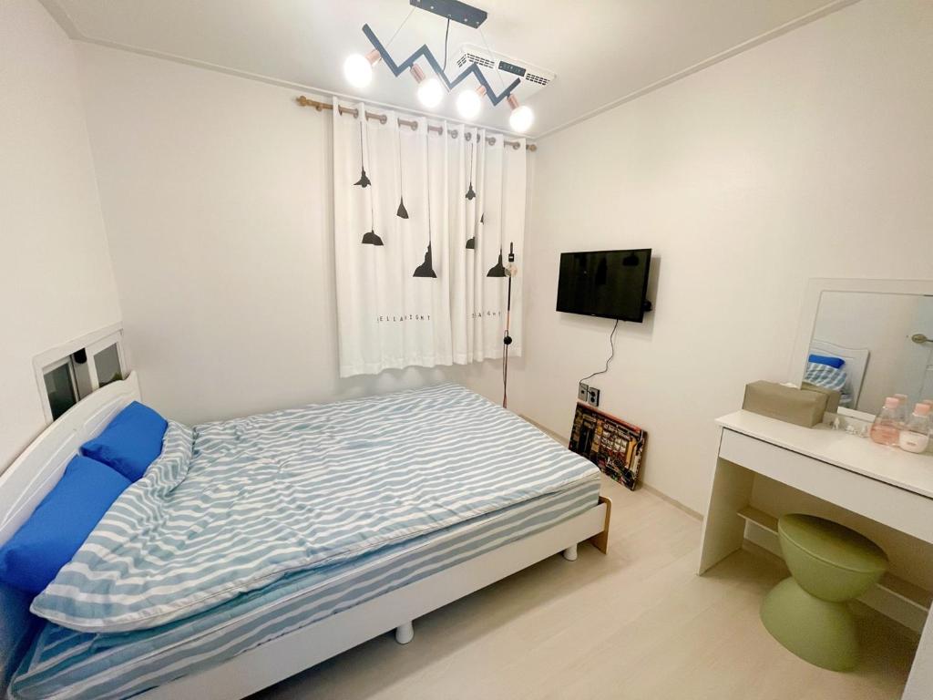 a white bedroom with a bed and a desk at Petit House in Sokcho