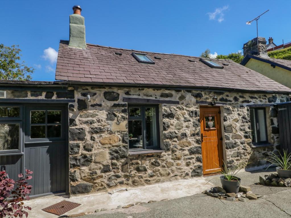 a stone cottage with a brown door and windows at Crabapple Cottage in Llanfairfechan