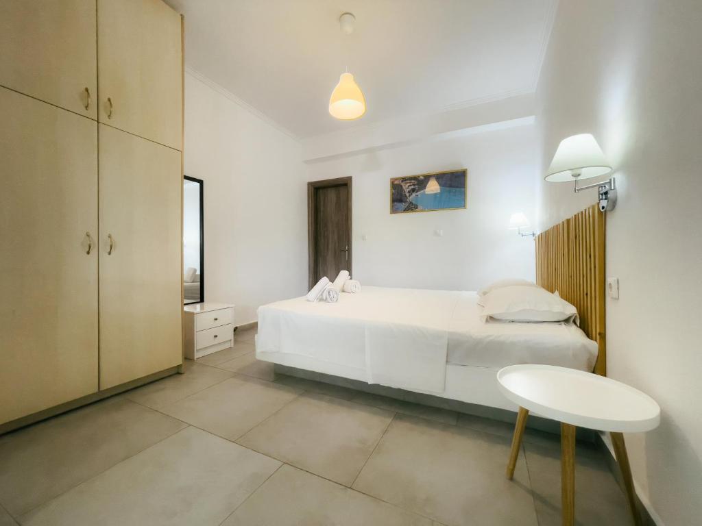 a white bedroom with a white bed and a table at Dionysia Rooms in Lefkada