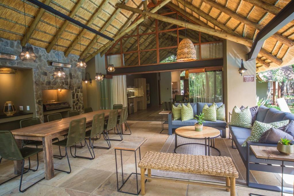 Kubu Metsi Lodge في Matlhagame: غرفة معيشة كبيرة مع طاولة وكراسي