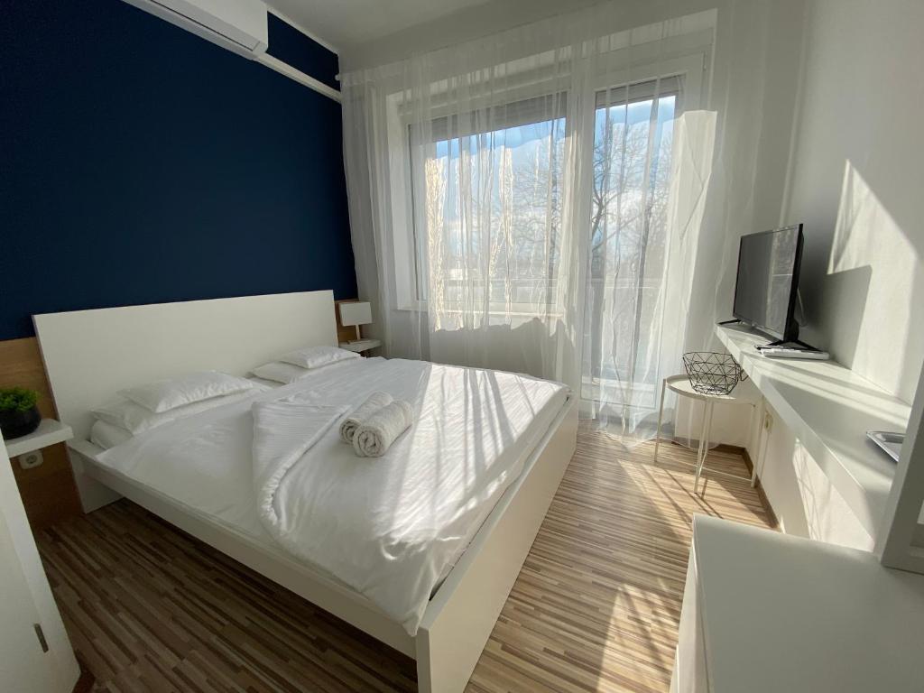 sypialnia z białym łóżkiem i telewizorem w obiekcie Élmény Balaton Hotel w Alsóörs
