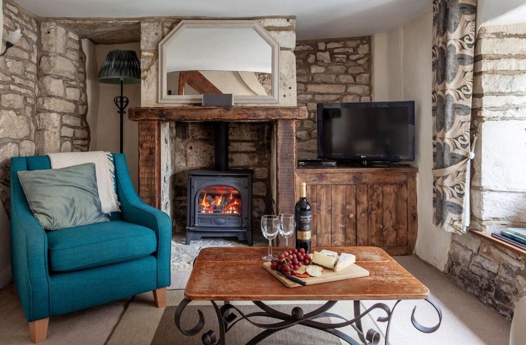 a living room with a blue chair and a fireplace at Teasel Cross Cottage, Painswick in Stroud