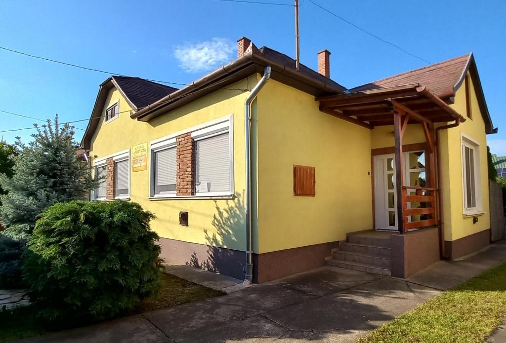 een geel huis met een veranda bij IldiMagdi Apartman in Hajdúszoboszló