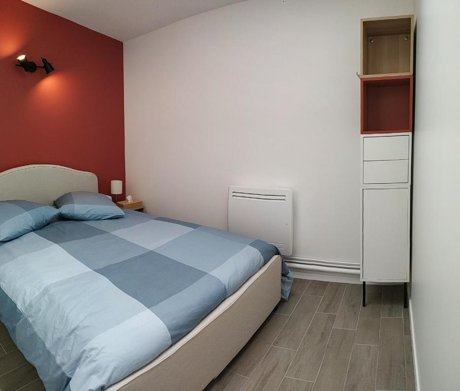 um quarto com uma cama e uma parede vermelha em Charmant et lumineux logement, au cœur de Cabourg em Cabourg