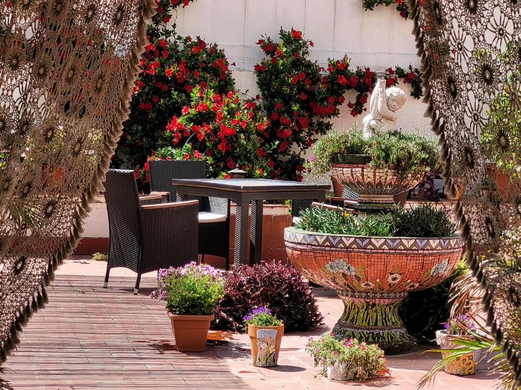 un patio con mesa, macetas y flores en Hostal LIWI, en Barcelona