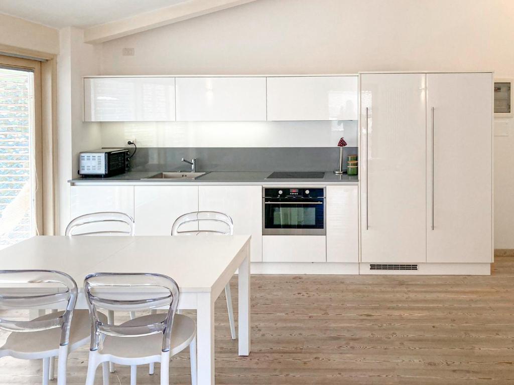 a kitchen with white cabinets and a white table and chairs at Elegante appartamento [Trento centro] Carpe Diem in Trento