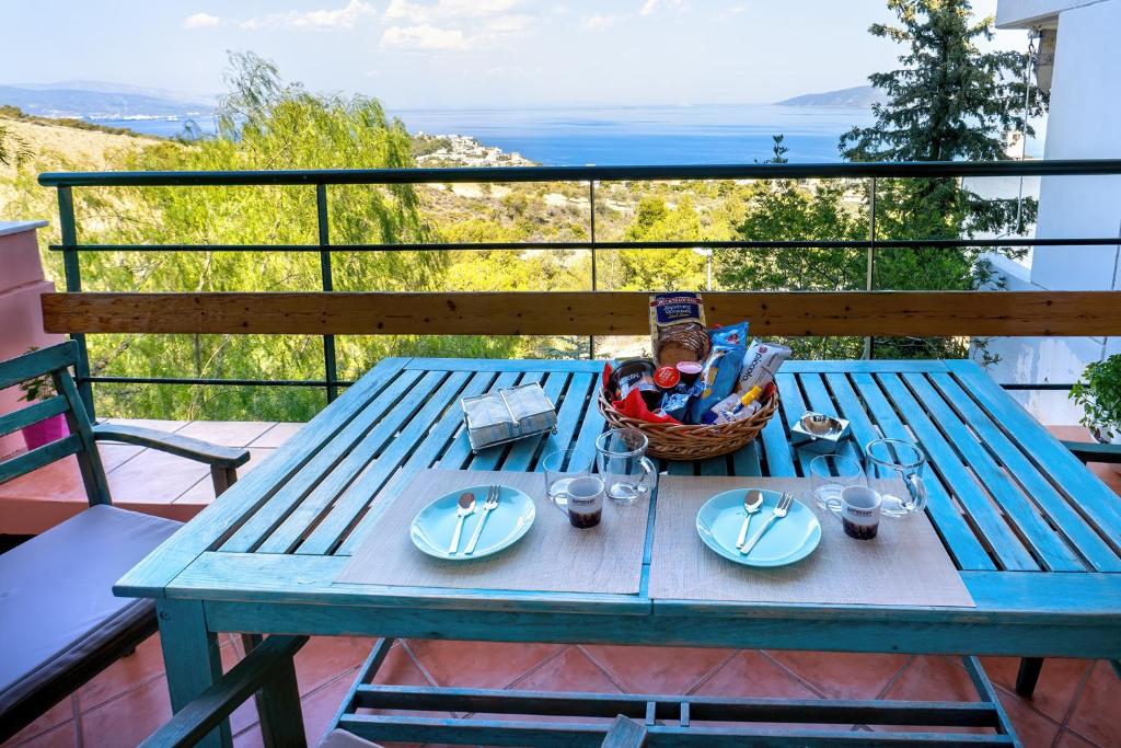 a blue picnic table with plates and a basket on a balcony at Vista sul Mare Loutra Oreas Elenis in Loutra Oraias Elenis