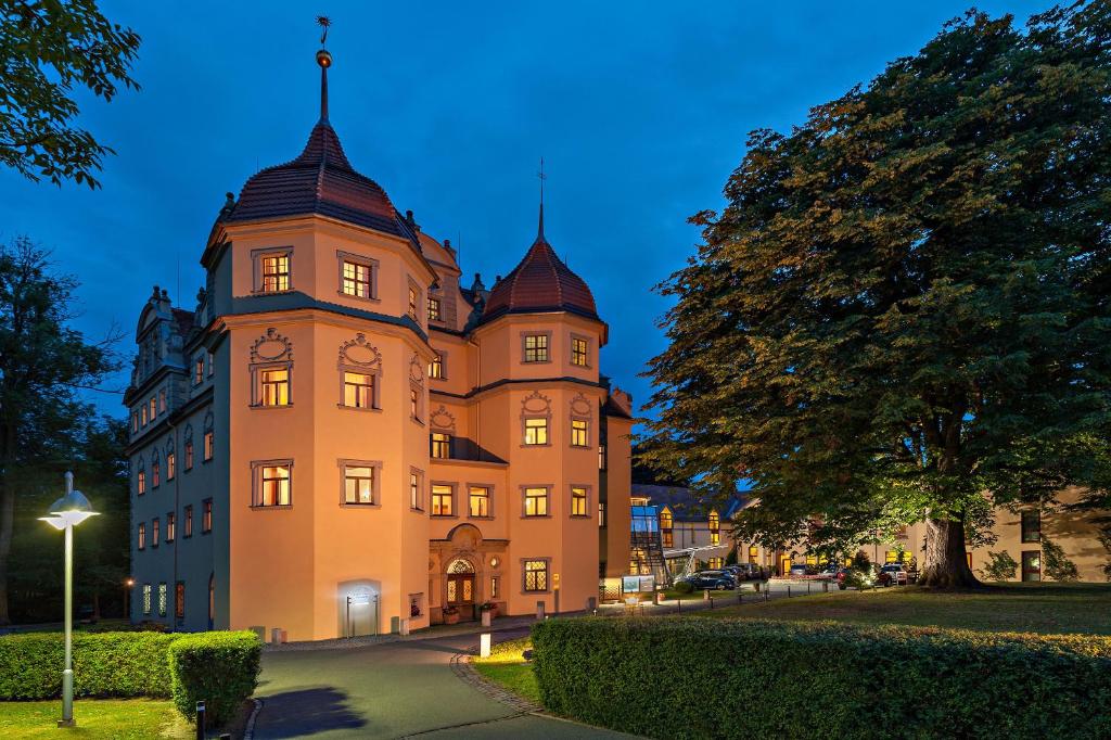 ein großes Gebäude mit einem Turm mit einer Uhr drauf in der Unterkunft Schloßhotel Althörnitz in Bertsdorf