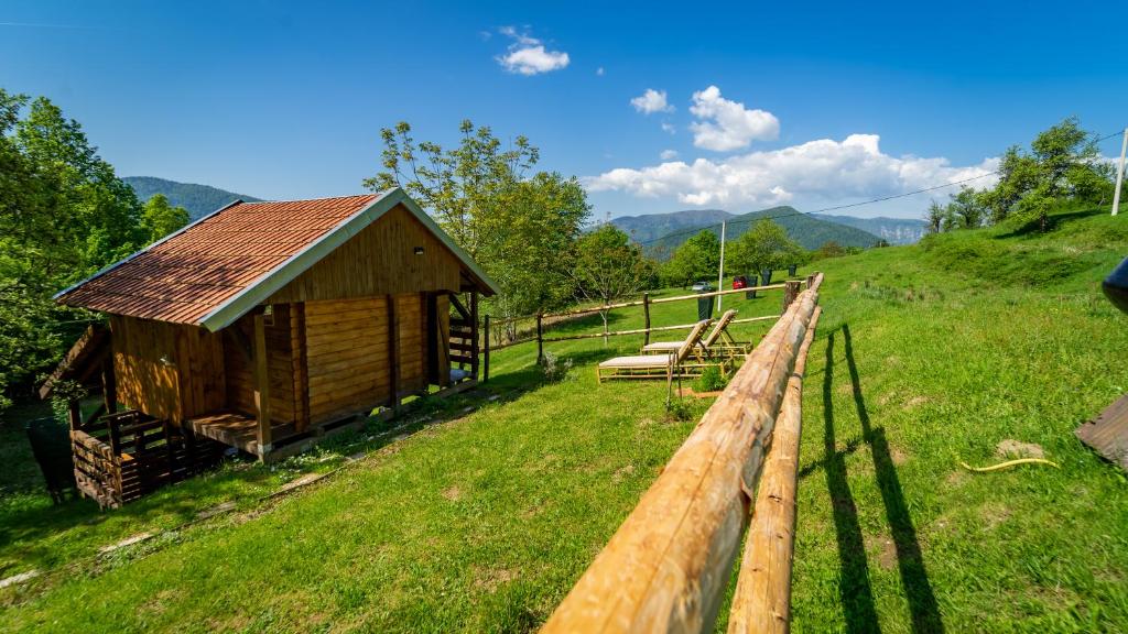 a wooden cabin in a field next to a fence at Robinzonski turizam "Robin` s Hood" in Skrad