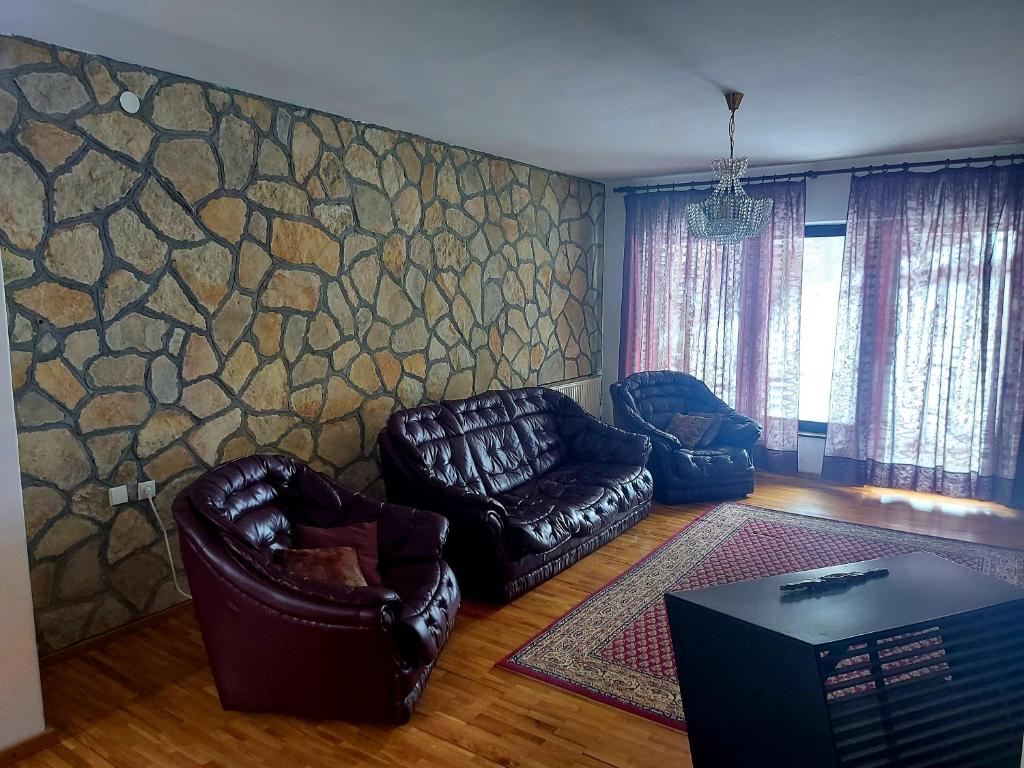 - un salon avec des fauteuils en cuir et un mur en pierre dans l'établissement Dom Kuća, à Kolašin