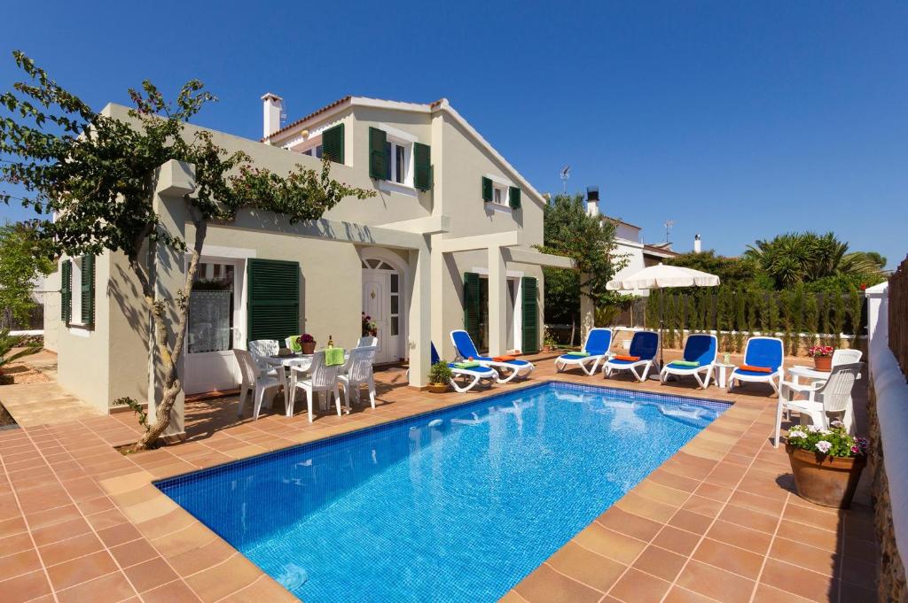 a villa with a swimming pool in front of a house at Villa Maggie by Villa Plus in Cala en Blanes