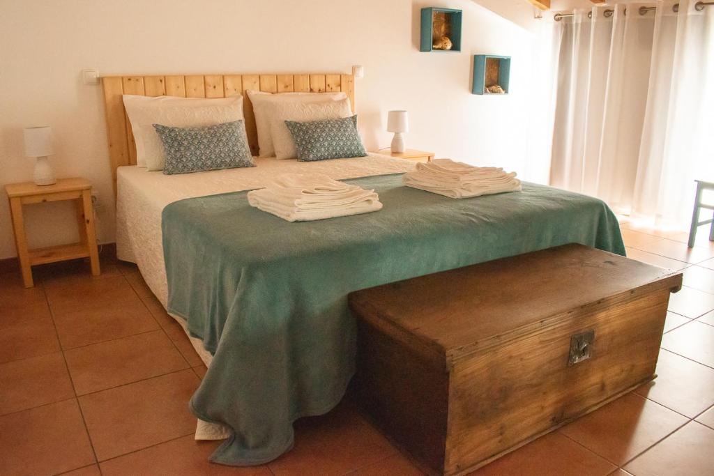 een slaapkamer met een groot bed en een groene deken bij Casa Ermelinda in Aljezur