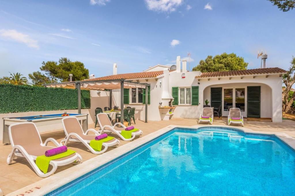 a swimming pool with chairs and a house at Villa Isi by Villa Plus in Cala en Blanes