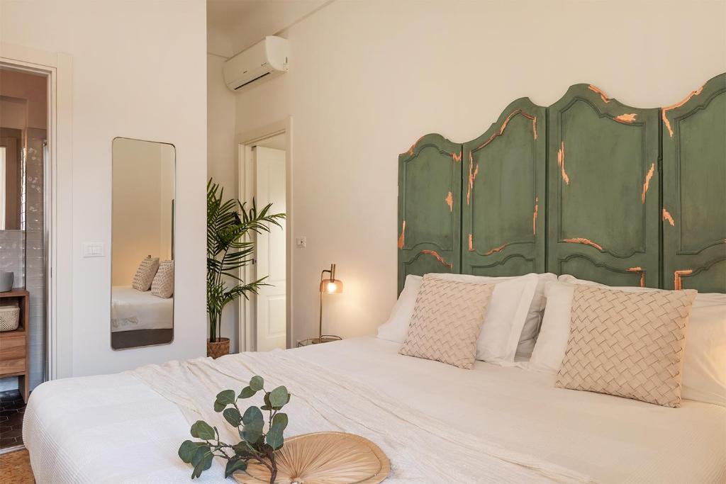 アラッシオにあるEnsemble rooms di Vayadùのベッドルーム1室(大型ベッド1台、緑の大きなヘッドボード付)