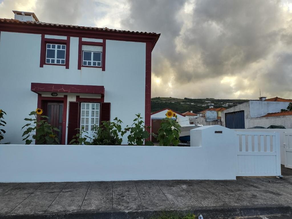 une maison blanche avec une clôture blanche devant elle dans l'établissement Villa Kai Casa frente al mar y completamente restaurada, à Santa Cruz das Flores