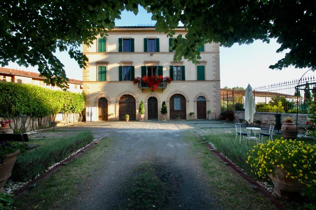 une grande maison avec une allée en face de celle-ci dans l'établissement Villa Sant’Andrea, à Sienne